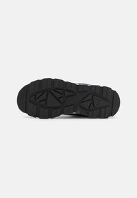 Semelle de chaussure en caoutchouc noir avec des rainures profondes et une surface texturée pour une meilleure adhérence, un motif de conception distinct et un bout arrondi.