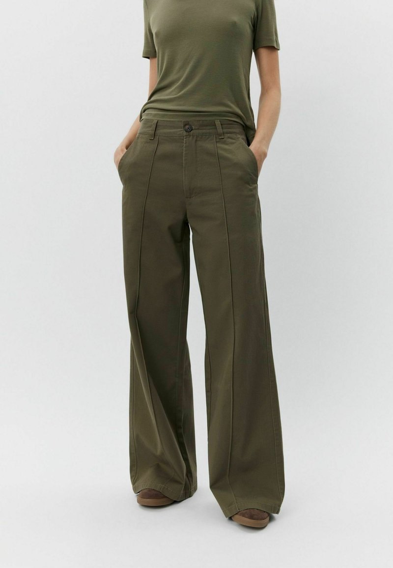 High-waisted, wide-leg trousers in olive green cotton with front pleats, side pockets, and a button closure.