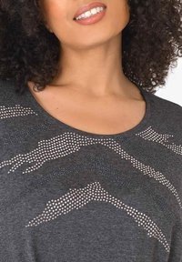 Šedý krátký rukáv top s kulatým výstřihem a abstraktním tečkovaným vzorem z kamínků po přední části, což přidává texturu a detail.