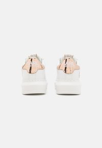 Baskets blanches avec un empiècement au talon en rose doré brillant, comportant le logo "KARL LAGERFELD", semelle blanche plate et tige en cuir lisse.