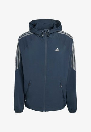 Laivastonsininen Adidas-huppari, jossa on etuvetoketju, joustavat hihansuut, vetoketjulliset sivutaskut ja kolme harmaata raitaa kummassakin hihassa.