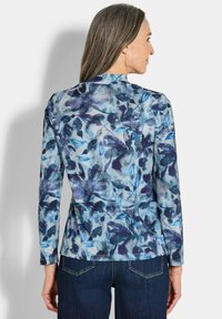 Langärmlige Bluse in einem blauen und lila Blumenmuster, mit einem weichen Stoff, einem runden Kragen und einer taillierten Passform.