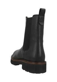 Botín Chelsea negro de cuero con panel lateral elástico, tira en el talón y suela gruesa negra con ribete marrón, en ángulo para mostrar la parte trasera y lateral.