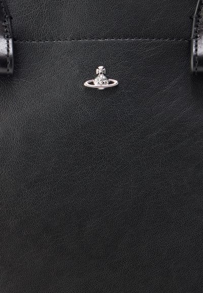 Fekete bőr kézitáska, texturált felülettel, középen egy kör alakú bolygó motívummal díszített fém kiegészítővel.