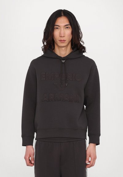 Hanorac gri închis cu logo text reliefat „EMPORIO ARMANI”, cordon reglabil și manșete ribbate. Material moale cu o croială lejeră.