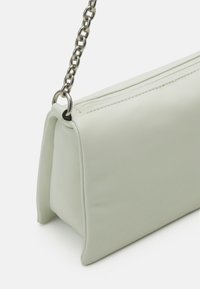 Borsa a mano in ecopelle verde chiaro con forma rettangolare. Dotata di una tracolla in catena argentata e chiusura con zip superiore. Texture liscia.