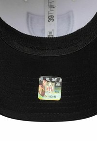Schwarze Stoffmütze mit glatter Textur und einem sichtbaren NFL-Logo-Sticker im Inneren. Das Design umfasst einen abgerundeten Schirm und einen engen Sitz.