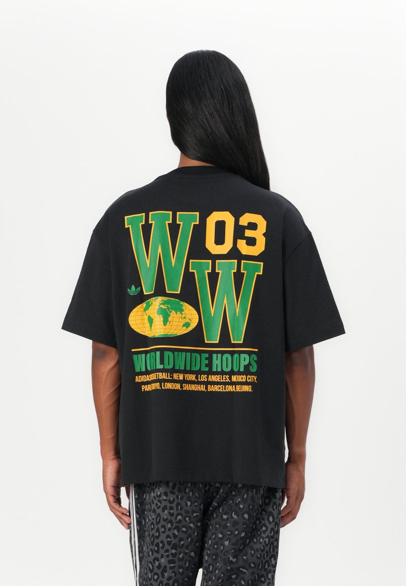 Svart oversized t-skjorte med grønn og gul grafisk tekst, et globusdesign, og "WORLDWIDE HOOPS" på baksiden.