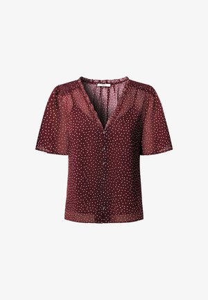 Blusa malva con lunares, mangas cortas abullonadas, escote en V y cierre delantero con botones. Presenta un tejido ligero y transparente con detalles de volantes.