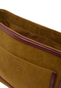 Sac en velours côtelé jaune avec un revêtement en cuir bordeaux, doté d'une poche avant et d'une fermeture à pression magnétique. Intérieur doublé de tissu lisse.