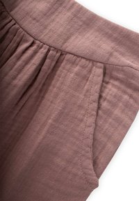 Svetlo mauve tkanina z gubanjem, ki ima nabran pas in stransko žep. Čisti šivi in mehak zaključek.