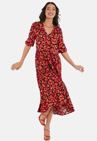 Robe maxi en tissu noir avec un motif floral vibrant en orange et rose. Présente un décolleté en V et des manches trois-quarts. Silhouette fluide.