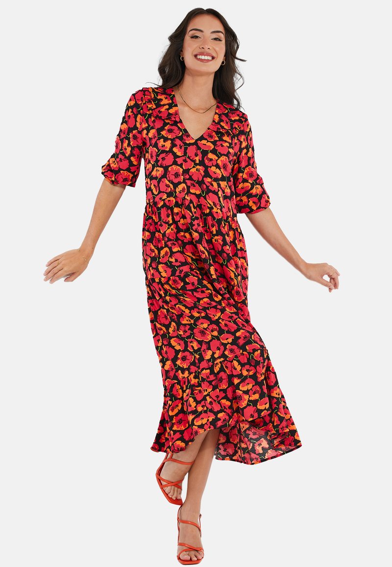 Robe maxi en tissu noir avec un motif floral vibrant en orange et rose. Présente un décolleté en V et des manches trois-quarts. Silhouette fluide.