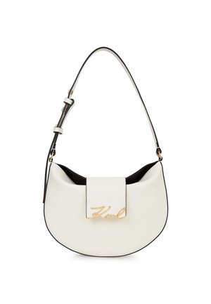 Sac à main en forme de croissant blanc avec bandoulière réglable et logo "Karl" en script doré sur le rabat avant, le tout sur un fond blanc uni.