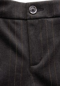 Černá látka s pruhovaným vzorem a texturovaným povrchem; obsahuje lesklý černý knoflík a detail boční kapsy.