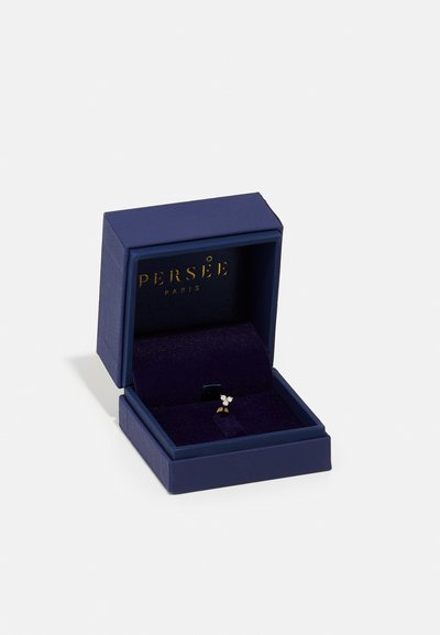 Marin fyrkantig ringask med guldbokstäver, invändigt klädd med mörkt tyg, som visar en delikat ring med en blommönster och små stenar.