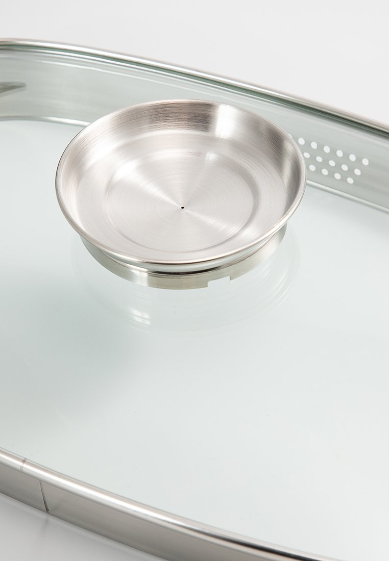 RVS kom met een geborstelde afwerking, geplaatst op een ronde basis; helder glas met ronde perforaties aan de randen.