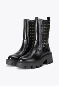 Czarne skórzane botki za kostkę z masywną czarną podeszwą, z teksturowanym tyłem i złotymi akcentami oraz dopasowaną cholewką.