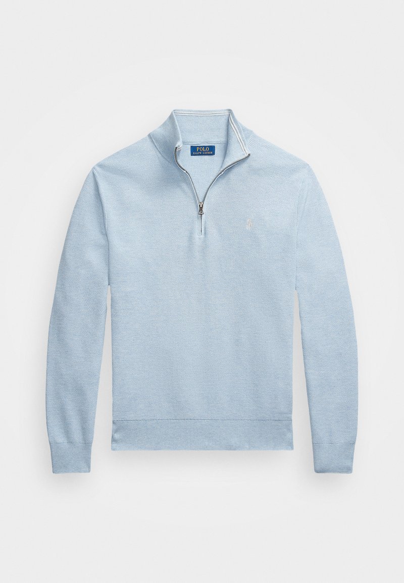 Lyseblå genser laget av teksturert stoff, med glidelås-lukking i kragen, lange ermer og en liten logo på venstre bryst.