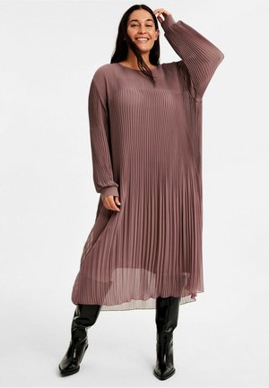 Fållad, långärmad midiklänning i dammig mauve, tillverkad av lättviktigt tyg. Har en avslappnad passform och en subtil lyster. Matchas med glänsande svarta stövlar.