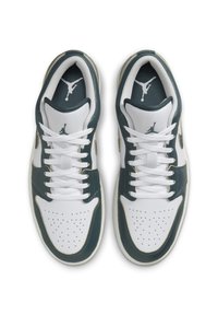 Vita och mörkgröna sportskor med perforerat tåparti, vita snören och gula accenter. Har en logotyp på tungan och sidorna.