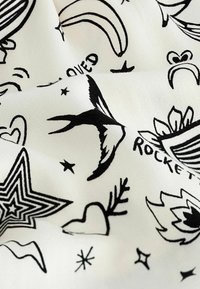 Witte stof met zwarte inktillustraties, waaronder sterren, harten, vogels en bananen. Het ontwerp heeft verschillende maten en vormen met een gladde textuur.