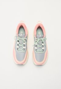 Des chaussures de sport grises et roses en tissu texturé, avec un design à lacets, un col rembourré et une semelle mouchetée.