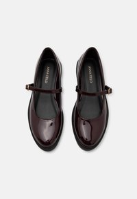 Chaussures Mary Jane en cuir verni bordeaux avec un bout rond, semelle noire et sangle ajustable dotée d'une boucle dorée. Surface lisse.