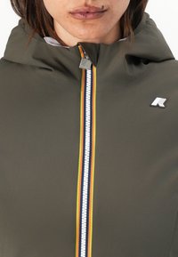 Olive green outerwear with a hood, featuring a front zipper decorated with red, yellow, and blue stripes, and a logo on the chest.
