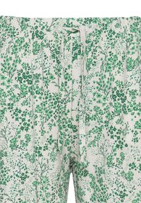 Pantalon beige avec imprimé floral vert et cordon de serrage ajustable en tissu à la taille élastique.