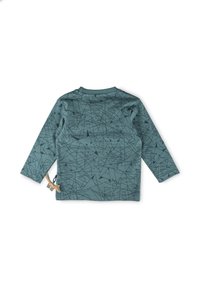 Langärmliges Hemd aus türkisfarbenem Stoff mit einem geometrischen schwarzen Muster. Enthält ein dekoratives, sandfarbenes Dinosaurier-Akzent auf der linken Seite.