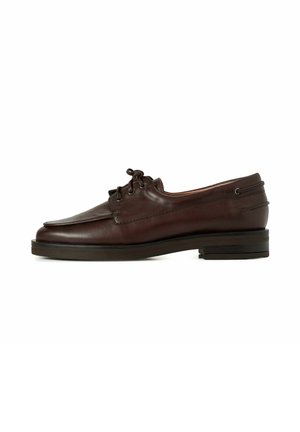 Bruine leren schoen met een ronde neus, twee oogjes voor veters, en een lage stapelhak. Glad textuur met subtiele stiksels.