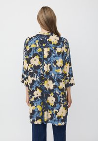 Bloemen tuniek top in blauw, geel en zwart. Kenmerkt zich door driekwart mouwen en een losse pasvorm. Getextureerde stof met een levendig patroon.