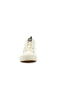 Sneaker bianco in tela con accenti neri, punta tondeggiante e suola in gomma testurizzata con un motivo a diamante. I lacci e la linguetta sono ben visibili.