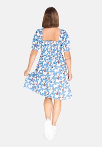 Vestido floral con patrón azul y blanco, mangas abullonadas y escote cuadrado. Hecho de tela ligera, cuenta con una cinturilla elástica.