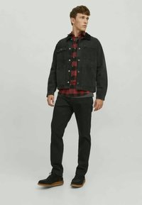 Must mustrakk üle punaste ja mustade ruutudega särk, koos mustade pükste ja mustade kingadega, millel on pruun tald. Lihtne disain ja sobivus.