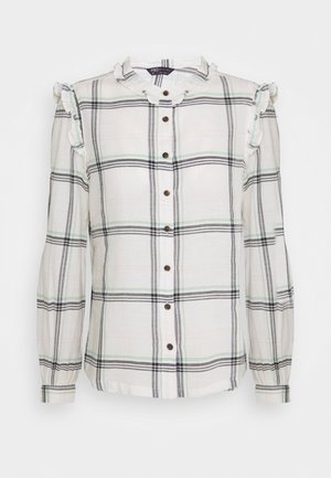 Weißes Karoshemd mit schwarzen, grünen und grauen Streifen, mit einem gerüschten Kragen und Ärmeln sowie braunen Knöpfen entlang der Vorderseite.