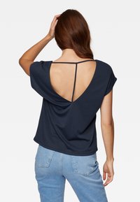 Top blu navy a maniche corte con scollo a V profondo sulla schiena, caratterizzato da una sottile tracolla sulle spalle e tessuto morbido e drappeggiato per il comfort.