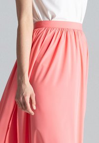 Koralle Maxi-Rock mit gerafftem Taillenbund, aus leichtem Stoff; glatte Textur und fließendes Design mit einem seitlichen Schlitz.