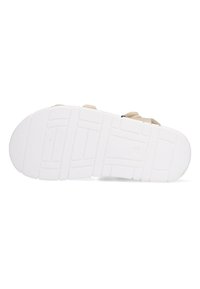 Witte rubberen zool met een textuurpatroon, een beige bovenkant en contrasterende donkere accenten voor extra detail.