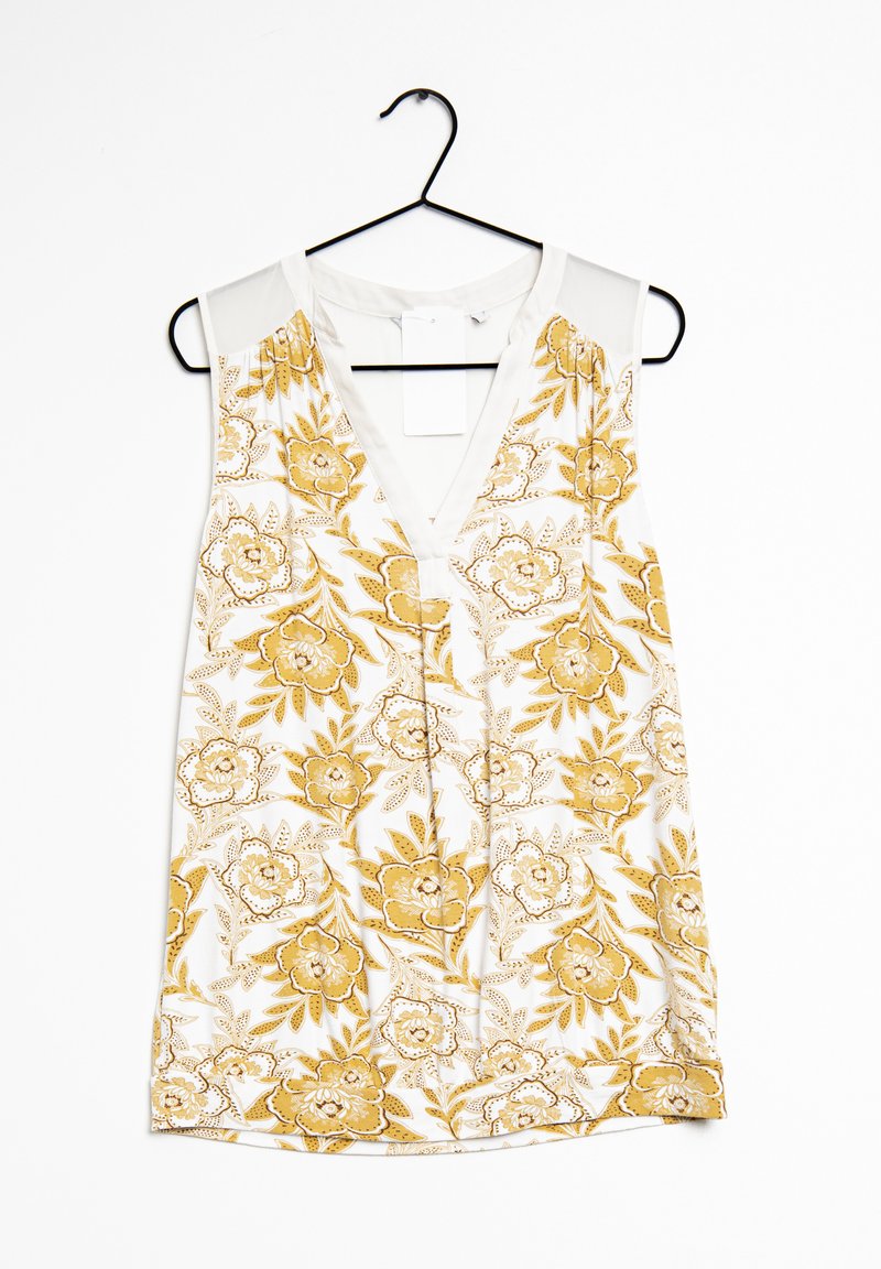 Sleeveless top with a V-neck, featuring a white fabric adorned with yellow floral patterns and green accents, hung on a black hanger.