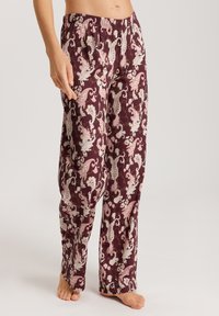 Ruitenbroek met bloemenpatroon in bordeauxrood met witte en roze paisley-ontwerpen. Het heeft een elastische tailleband en rechte pijpen.