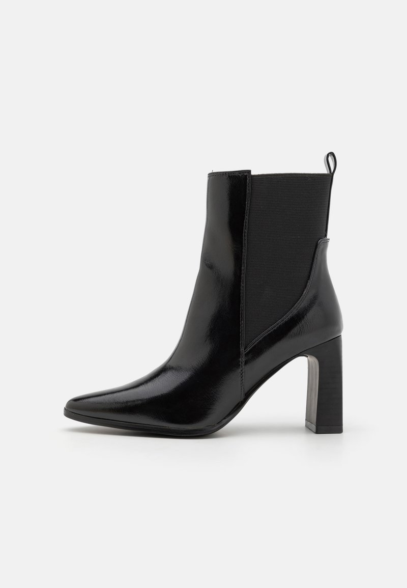 Bottine en cuir verni noir avec bout pointu, talon carré, empiècement latéral élastique et languette à l'arrière.