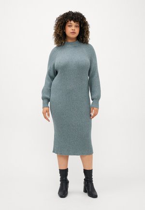 Light blue ribbed knit midi dress with long sleeves and a high neck. Worn with black ankle boots, featuring block heels.