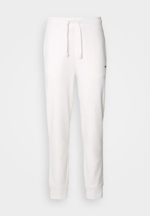 Biele bavlnené tepláky s elastickým pásom, šnúrkou a rebrovanými manžetami. Obsahujú malé čierne logo na boku.