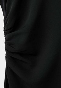 Gros plan sur un tissu noir avec un détail de fronces réunies créant des plis texturés sur le côté gauche.