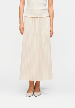 Φούστα μάξι σε ανοιχτό μπεζ χρώμα με κάθετες ριγέ σε παστέλ αποχρώσεις, ελαστική ζώνη μέσης και λεία υφή, συνδυασμένη με γκρι ανοιχτά παπούτσια με μυτερή μύτη.