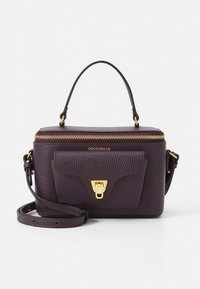 Lilla læderhåndtaske med en tekstureret overflade, guldlynlås og detaljer. Har et øverste håndtag og en aftagelig rem samt en forlomme.