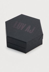 Cutie hexagonală neagră cu un finisaj texturat și inscripția "LUV AJ" în relief, de culoare mov închis, pe capac, concepută pentru bijuterii sau obiecte mici.