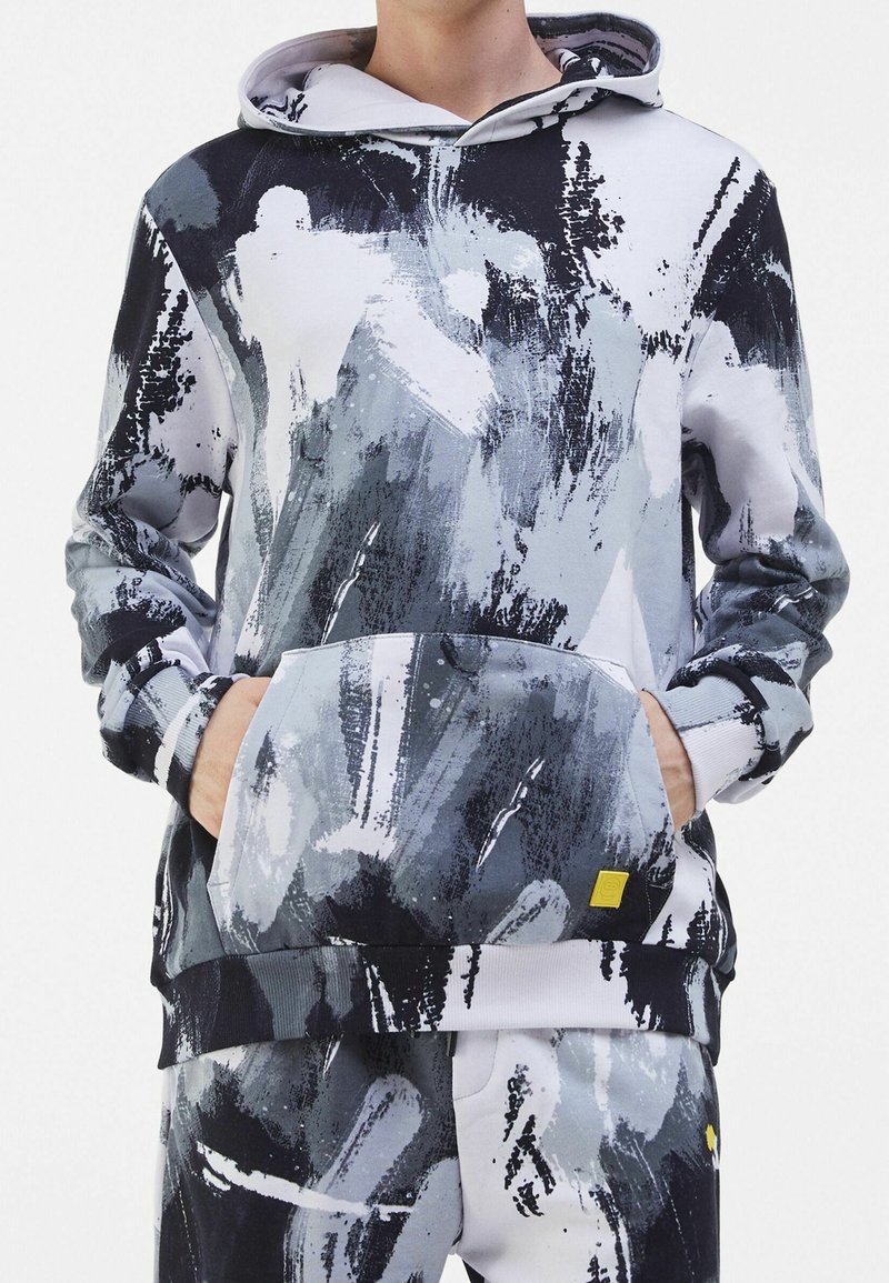Felpa con cappuccio con motivo astratto a pennellate in grigio, nero e bianco. Presenta una tasca frontale e dettagli a costine su polsini e orlo.
